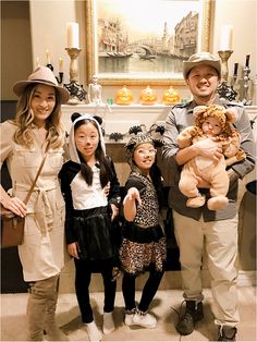 four people standing in front of a fireplace holding stuffed animals