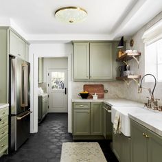 a kitchen with green cabinets and white counter tops, along with black tile flooring