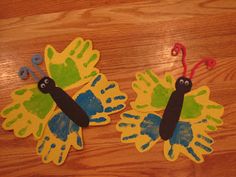 two paper butterflies on a wooden surface with one painted yellow and the other blue, sitting next to each other