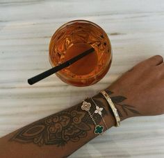 a person's arm with two bracelets and a drink