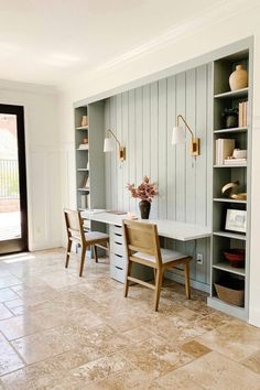 a room with two chairs and a desk in the center, next to a bookshelf