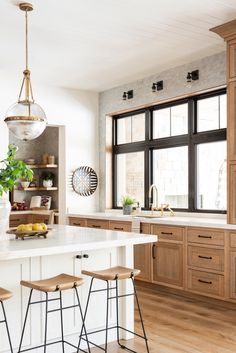 a large kitchen with wooden cabinets and stools in front of the countertop area