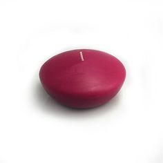 a red candle sitting on top of a white surface