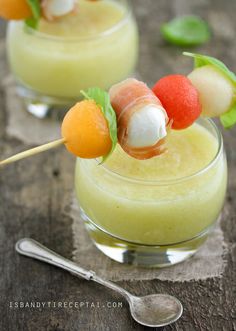 two small glasses filled with fruit and marshmallows on top of a wooden table