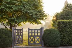 a wooden gate in the middle of some bushes