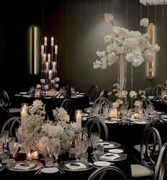 a dining room set up with black tables and white flowers on the centerpieces