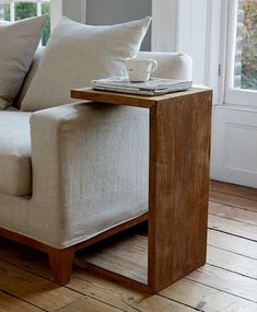 a white couch sitting on top of a hard wood floor next to a wooden table