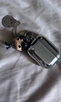 a cell phone keychain that is laying on top of a white bed sheet