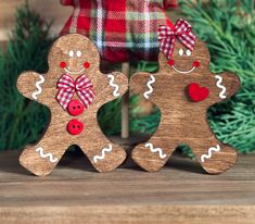 two wooden gingerbreads with red buttons and bows on their heads are standing next to each other