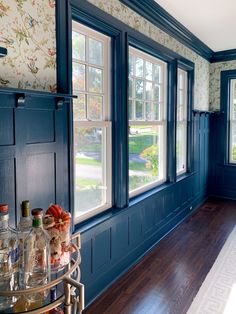 an empty room with blue walls and wood flooring is pictured in this image, there are many bottles on the table