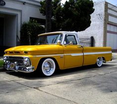 an old yellow truck parked in front of a building