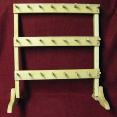 an old fashioned wooden shelf with four hooks on it's sides and two wheels attached to the bottom