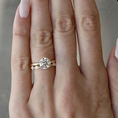 a woman's hand with a diamond ring on top of her finger and the other hand holding an engagement ring