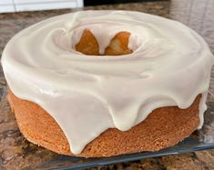 a cake with white icing on top of a glass plate sitting on a counter