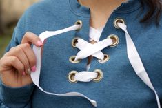 a woman wearing a blue jacket and white ribbon around her neck holding something in one hand