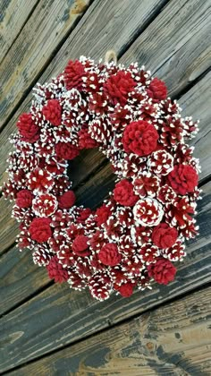 a red and white wreath on a wooden fence