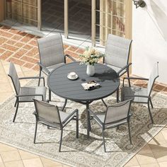 an outdoor table and chairs on a patio with a rug in front of the door