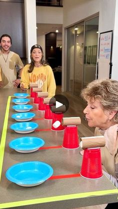 a group of people standing around a table with red and blue cups on it,