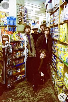 a group of young men standing in front of a store shelf filled with drinks and condiments