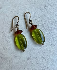 "olive green earrings   green brown earrings   czech glass earrings These transparent olive green beads are Czech glass, slightly twisted rectangles. Each is topped with an amber brown glass saucer bead. Hook ear wires are antiqued brass. Length of earrings from top of ear wires is 1 1/2\".  Green beads measure 14mm long, about 1/2\". You can enter my shop here: gypsydangles.etsy.com" Earthy Green Earrings, Olive Green Earrings, Olive Aesthetic, Earthy Green Dangle Earrings, Earthy Brown Czech Glass Jewelry, Green Czech Glass Dangle Beaded Earrings, Brown Czech Glass Bead Earrings, Dangle Bead Earrings, Olive Earrings