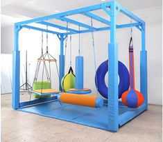 an indoor play area with swings, balls and other toys on the floor in front of a white wall