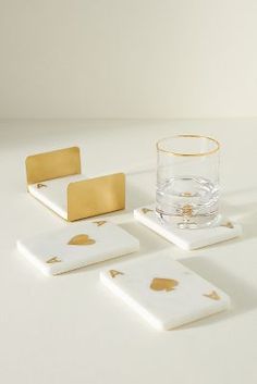 four coasters with gold leaf designs and a glass on the bottom one is empty