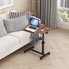 a laptop computer sitting on top of a wooden table next to a white couch in a living room