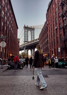 a woman is walking down the street in front of some tall buildings and a bridge