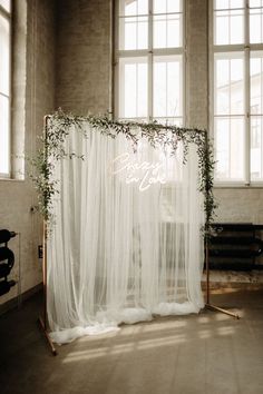 a white wedding backdrop with greenery on it