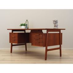 a wooden desk with two drawers and a vase on the top shelf next to it