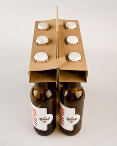 two brown beer bottles sitting next to each other in front of a box with white caps