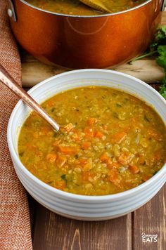 a bowl of soup with carrots and celery next to a pot of stew