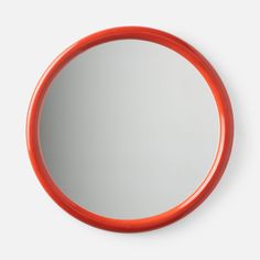 an orange circular mirror on a white wall