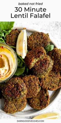 a white plate topped with falafel next to lemon wedges and lettuce