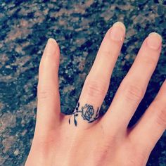 a person's hand with a flower tattoo on their left thumb and the middle finger