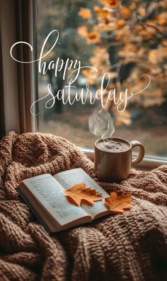 a cup of coffee and an open book on a blanket with the words happy saturday