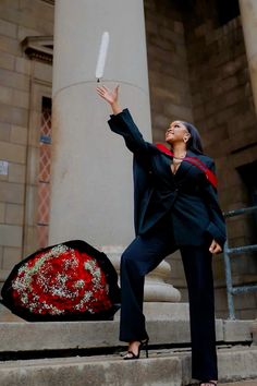 a woman in a black suit and red stoler holding up a white object