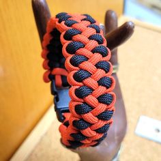 an orange and black braided bracelet on a mannequin's head in front of a wooden door