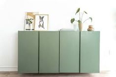 a green cabinet with plants and pictures on top