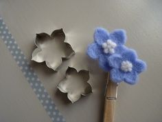 three cookie tins with flowers on them next to a wooden spoon and blue polka dot ribbon