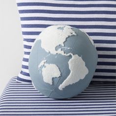 a blue and white striped pillow with an earth globe on it's backrest