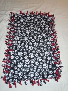 a black and white dog paw print blanket with red tassels on the edges