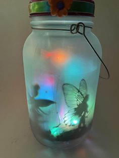 a jar that has some lights in it and a butterfly on the inside of it