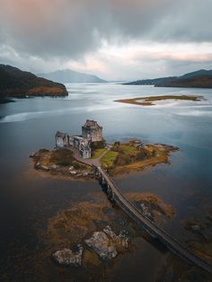 an aerial view of a castle in the middle of a body of water with a bridge leading to it