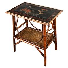 a wooden table with a black top and floral designs on the side, against a white background