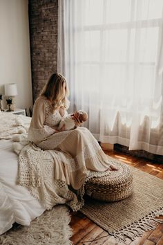 a woman sitting on top of a bed next to a window