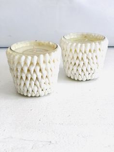 two white candles sitting next to each other on a table