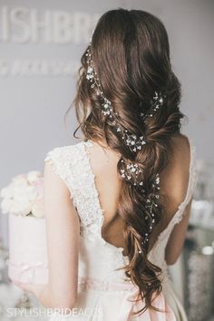 the back of a bride's head with flowers in her hair, holding a wedding cake