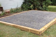 a wooden frame with gravel in front of a house