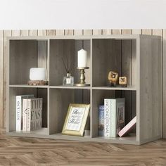 an open book shelf with books and candles on it in a room that has wood flooring